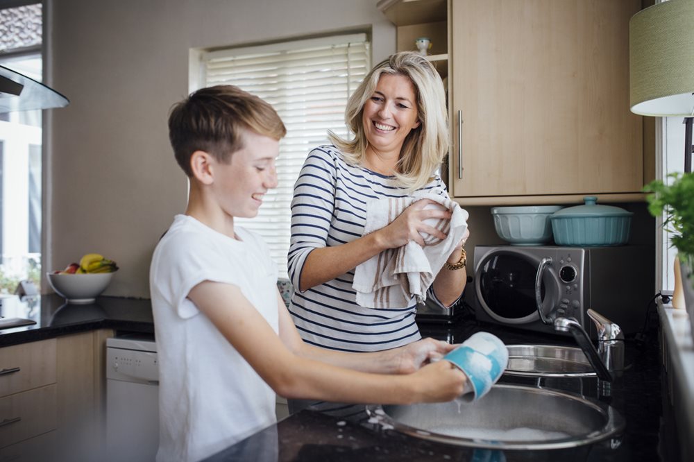 Mother and son doing the dishes in kitchen