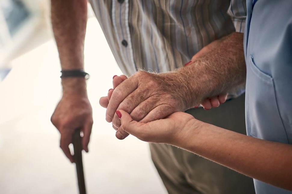 Carer helping elderly man walk