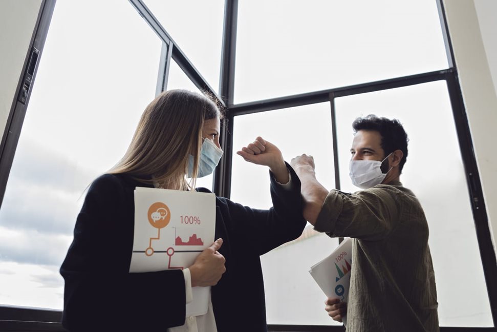 Colleagues elbow bump after returning to work