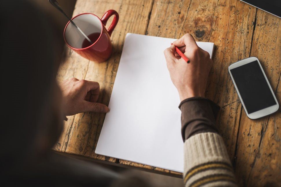 Man taking notes from his laptop at home