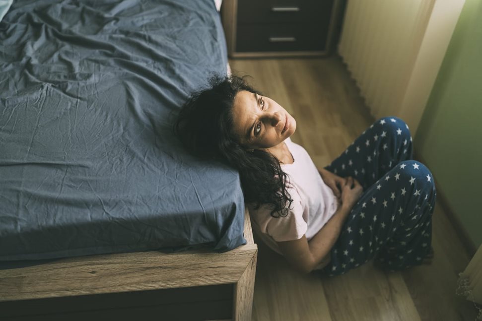 Sad woman sitting on the floor in bedroom