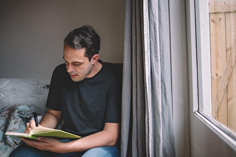 Man taking notes in his journal at home