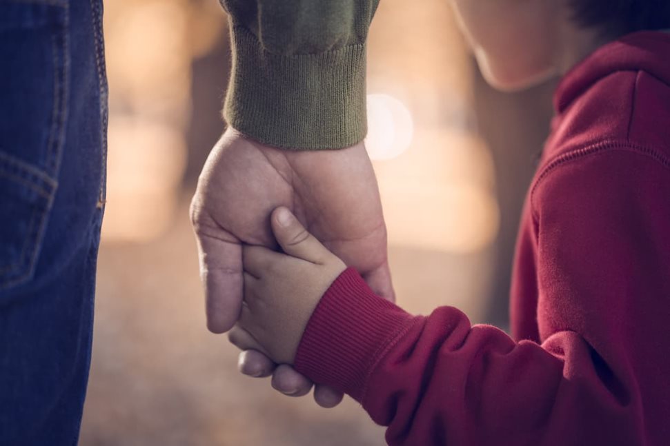 Parent holding their young child's hand