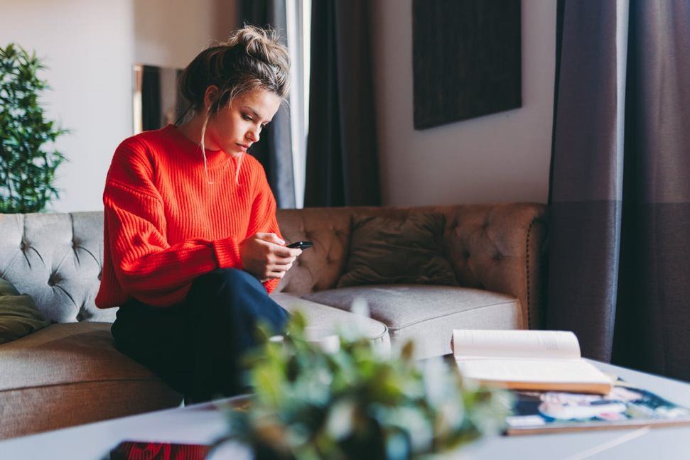 Woman on her phone sitting on the couch