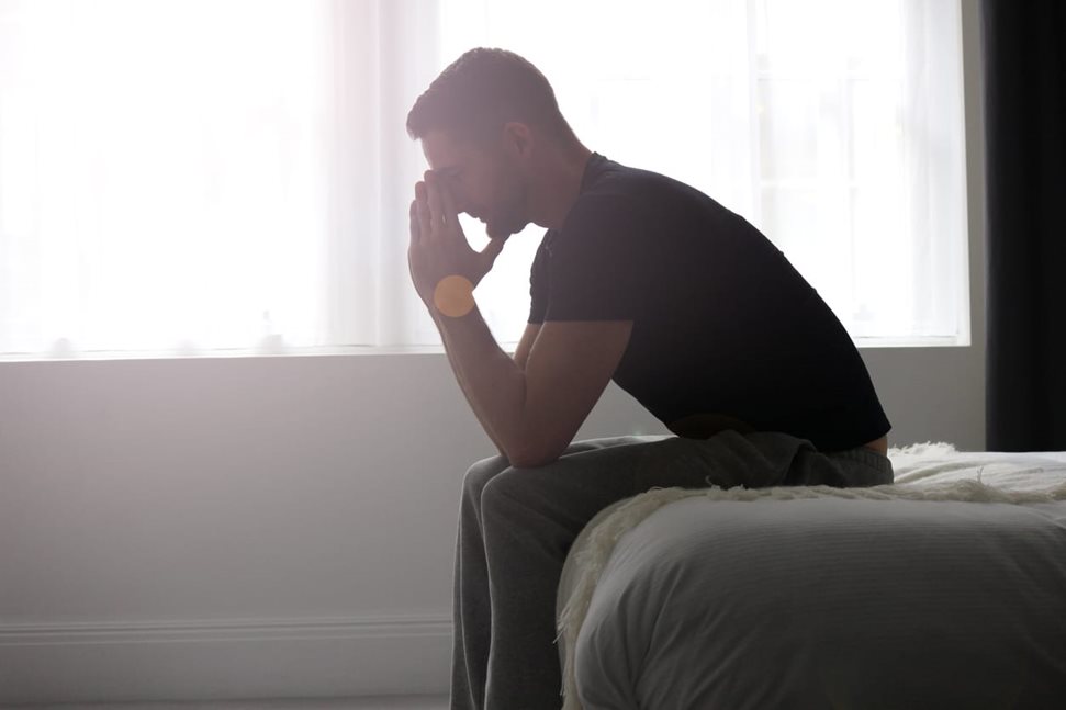 Worried man sitting on edge of bed
