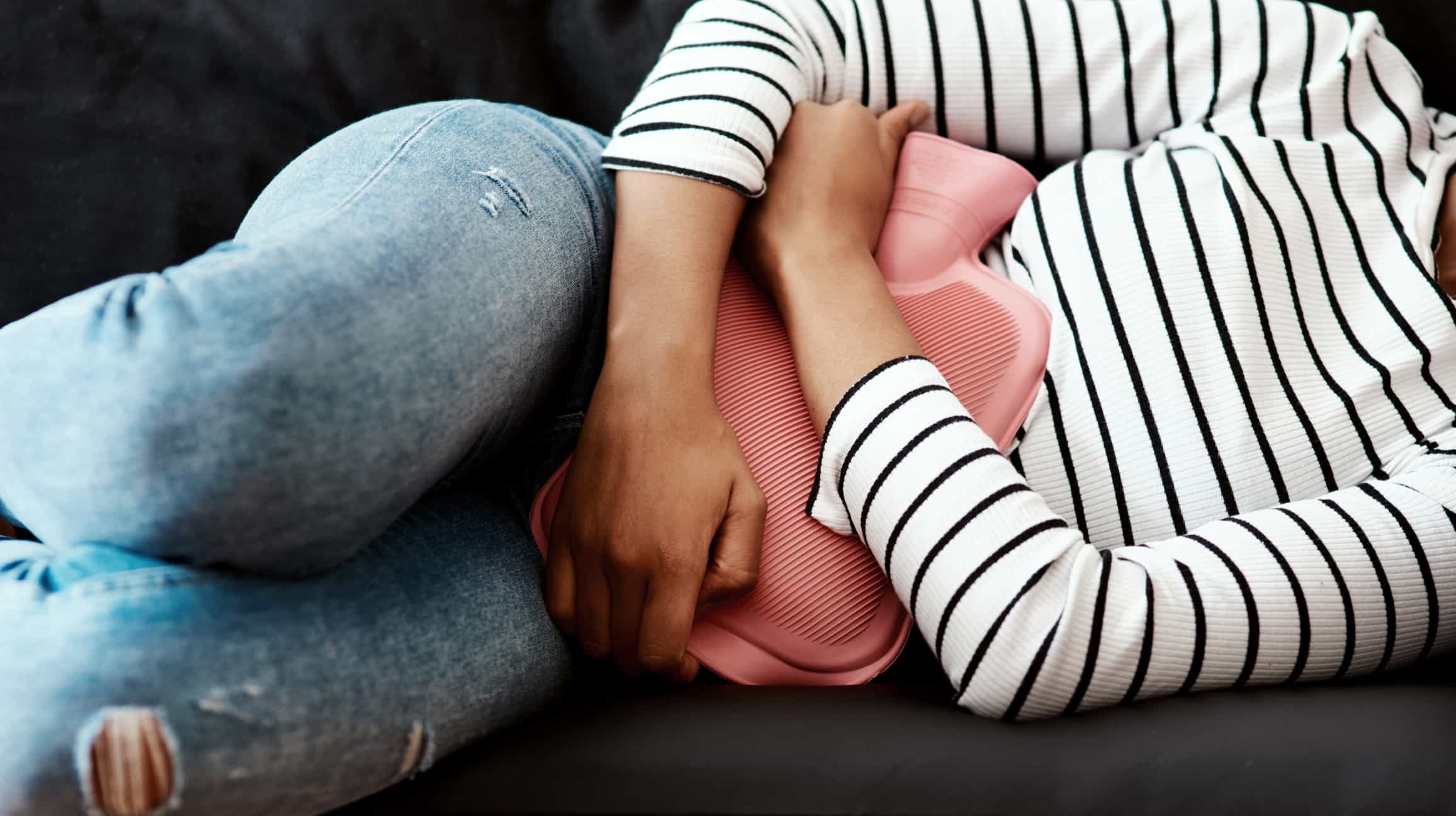 Woman holding hot water bottle to her stomach