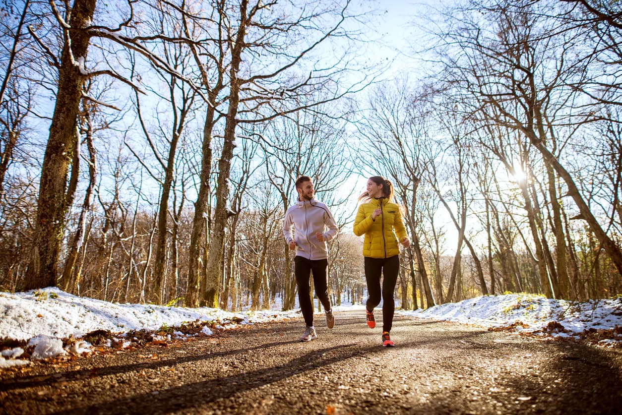 Friends jogging in park wrapped up in warm clothes