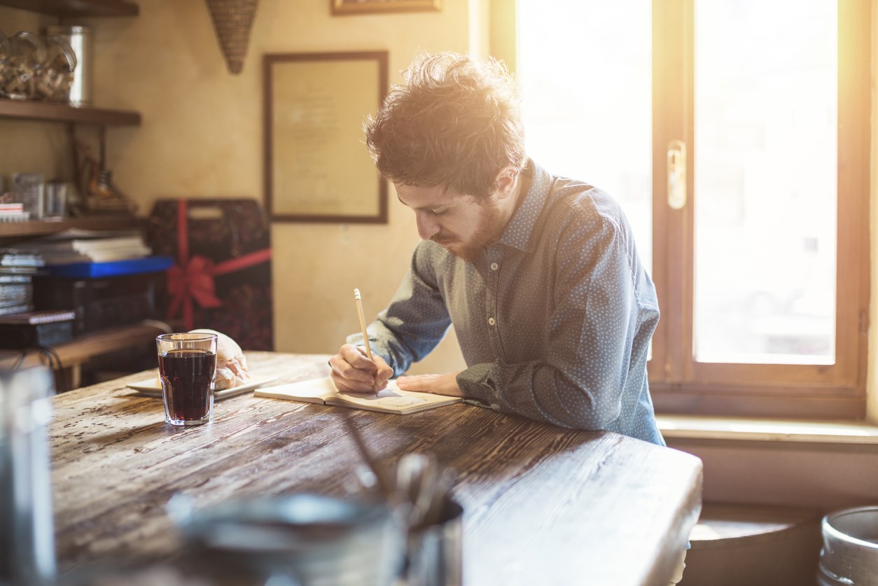 man writing in café