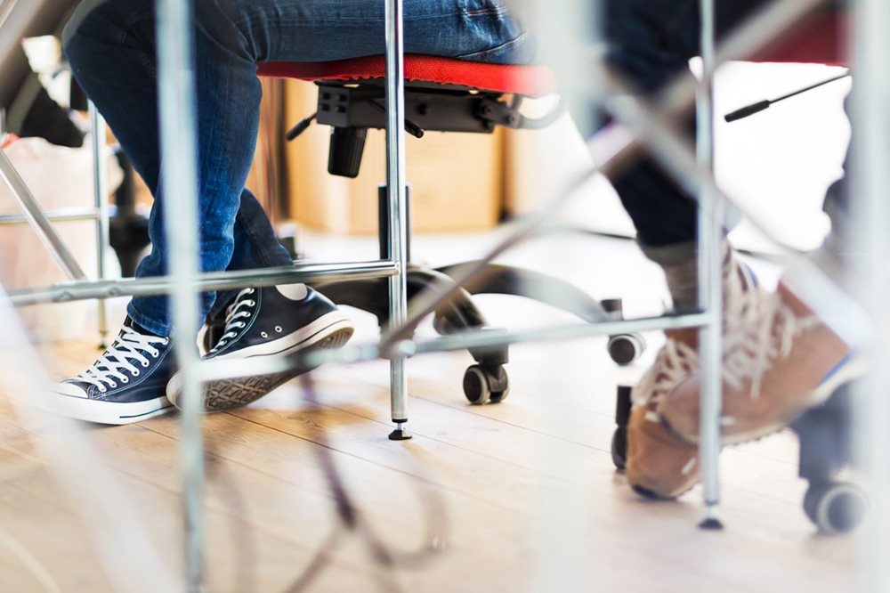 feet of person sitting at desk in work
