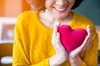 Woman in yellow jumper holds heart
