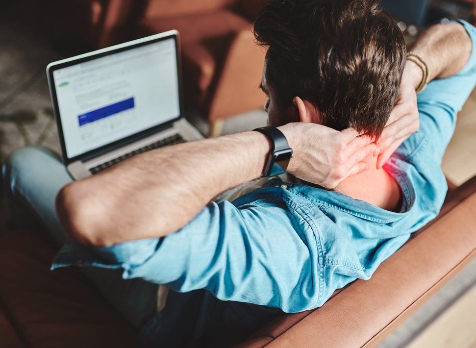 Man with laptop massaging his sore neck