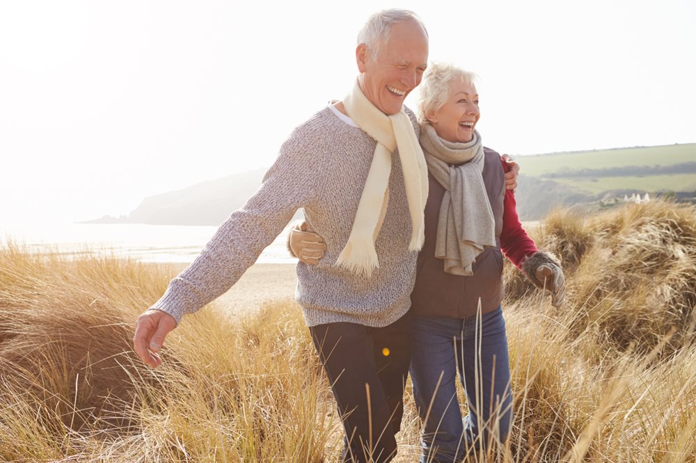 Elderly couple enjoying coastal walk in sunshine