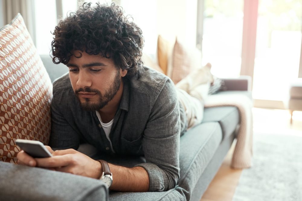 man looking at phone on couch