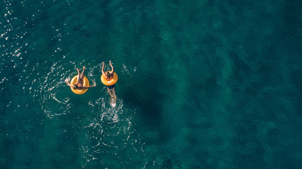 Couple swimming in the sea with inflatable rings